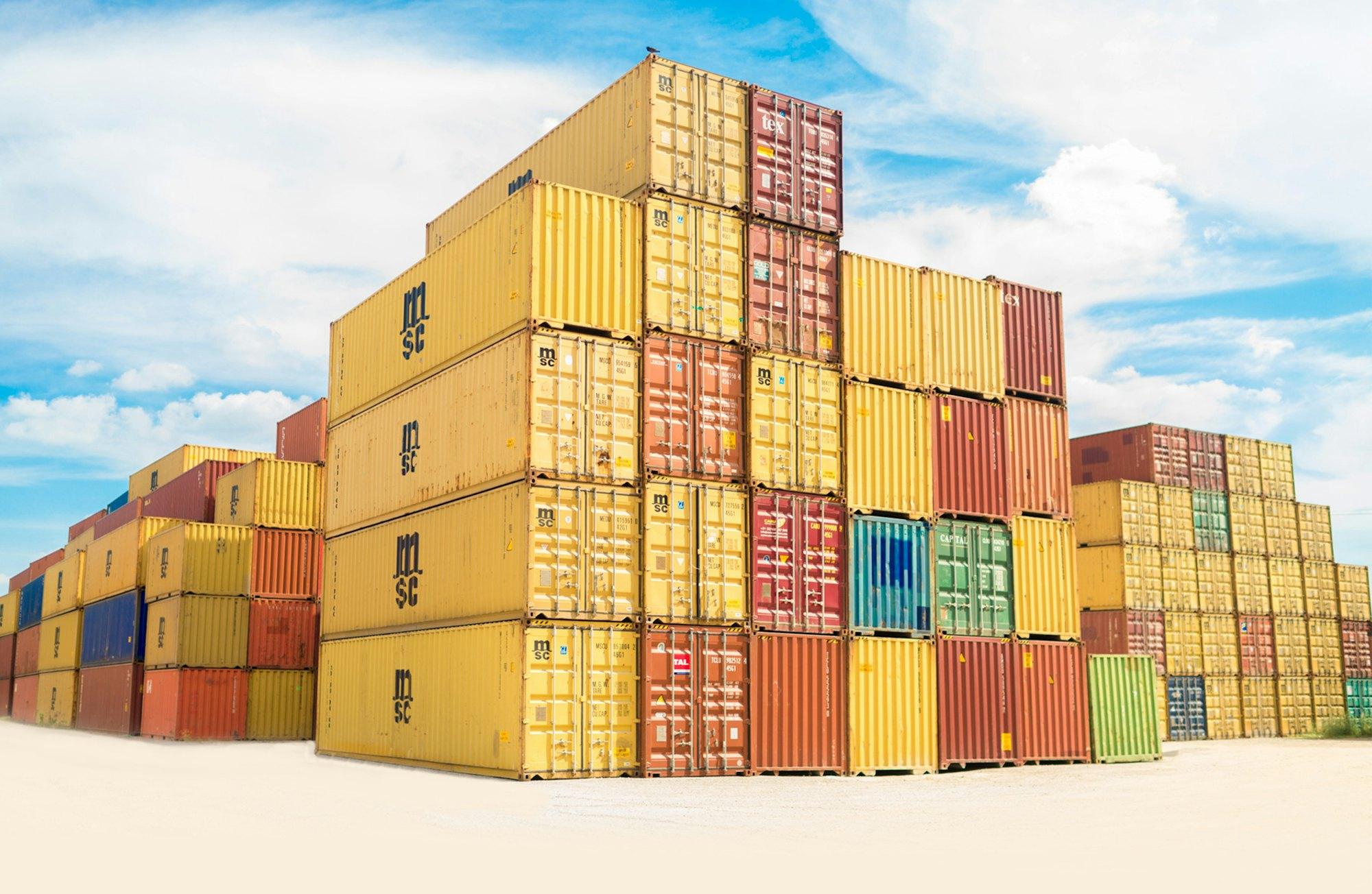 Stacks of shipping containers under a blue sky
