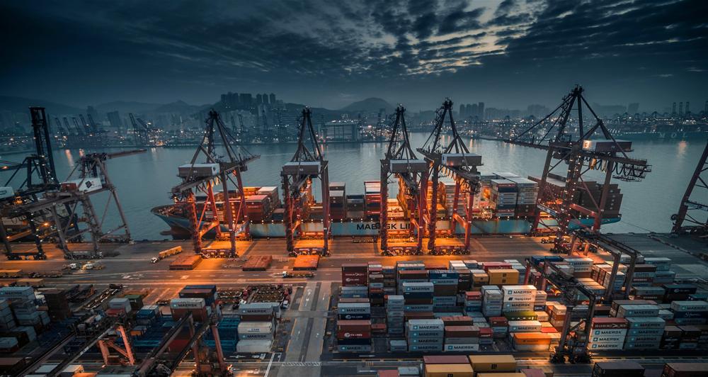 Container terminal with cranes and stacked boxes at dusk
